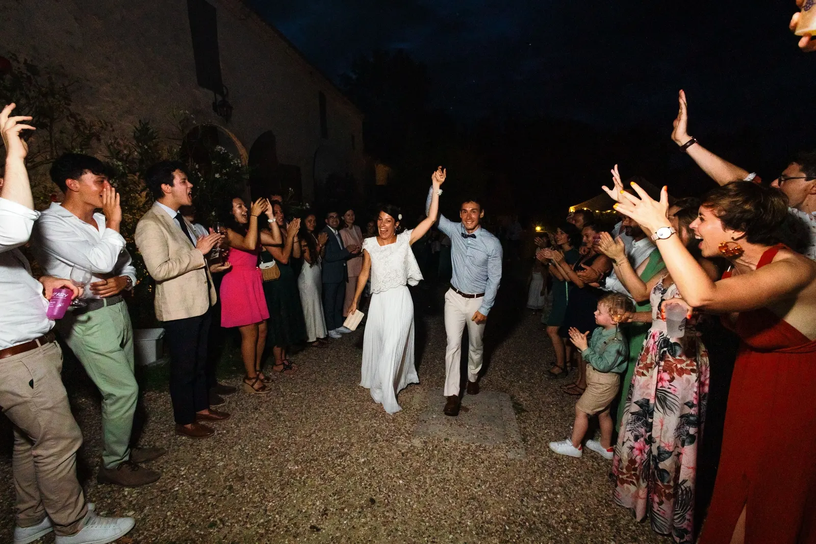 L'arrivée des mariés le soir, entre deux haies d'invités qui applaudissent